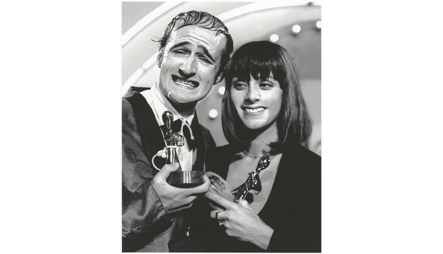 Black and white photo of Norman Gunston and Denise Drysdale smiling and holding up two Logie Awards trophies