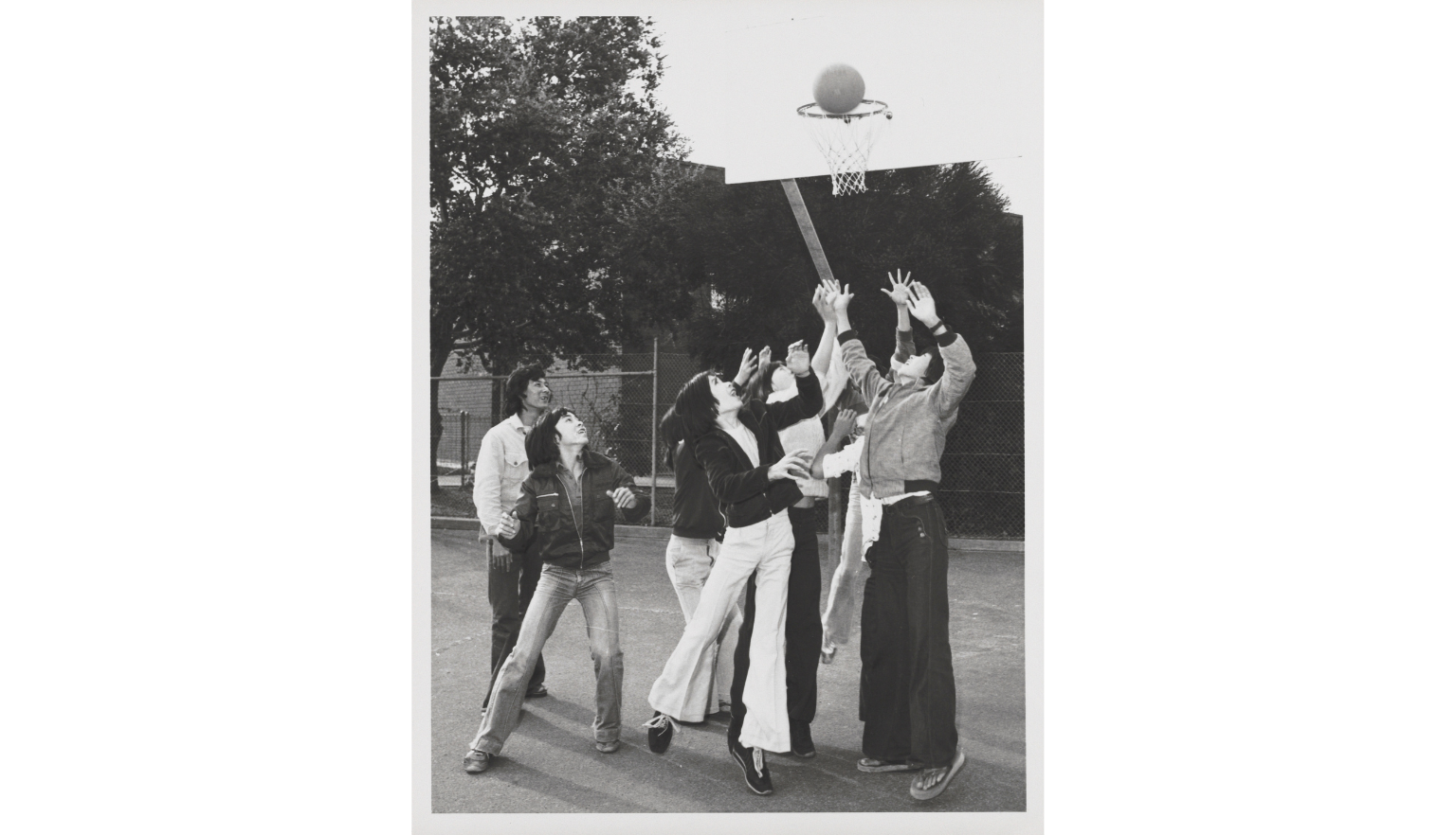 A black and white photograph showing a group of people playing netball