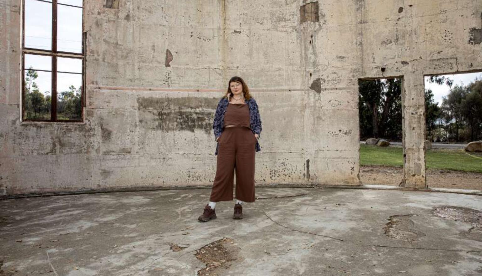 Karlie Noon standing in the burnt remains of a telescope at Mount Stromolo Observatory
