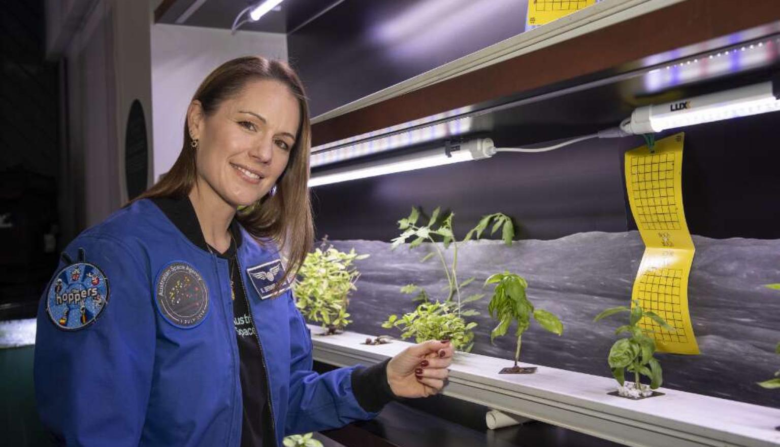 Katherine Bennell-Pegg standing next to plant samples in a lab