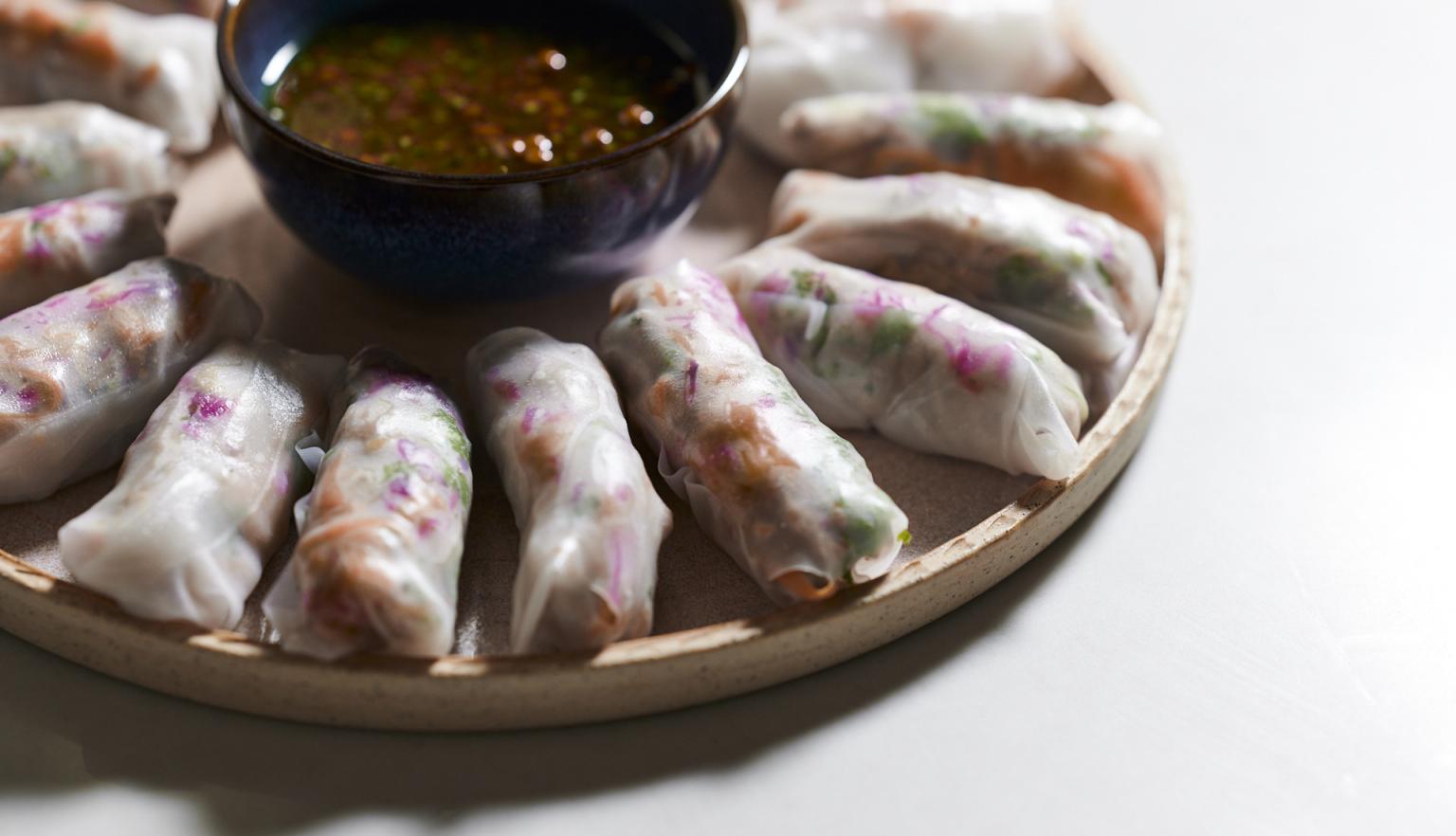 Spring rolls arranged in a circle on a tray with a dipping sauce