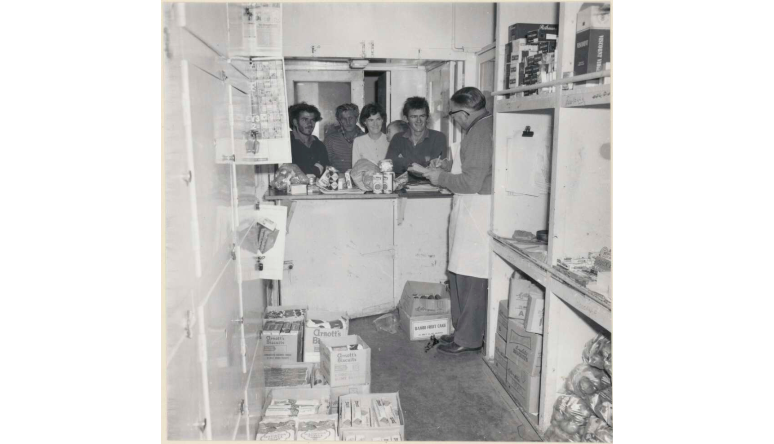 Three men and a woman holding a child at the provision store on the Tea and Sugar train on the Trans Australia Railway
