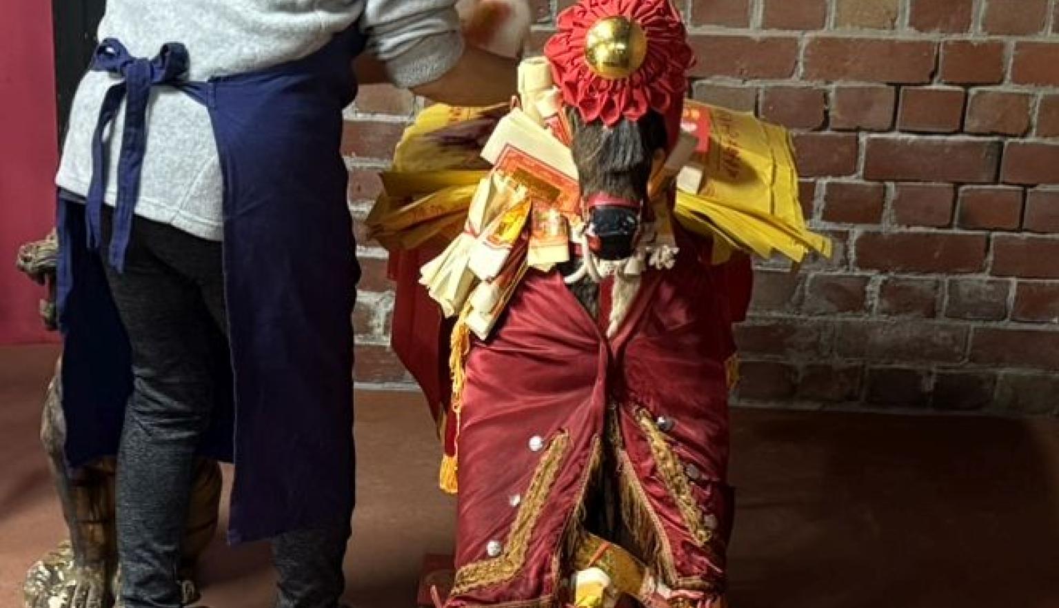 A person stands next to the statue of a horse and applies dressings to it. 