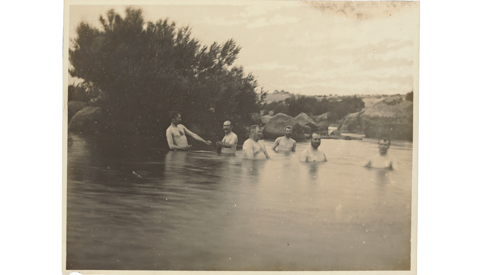 Six men chest-deep in a  river