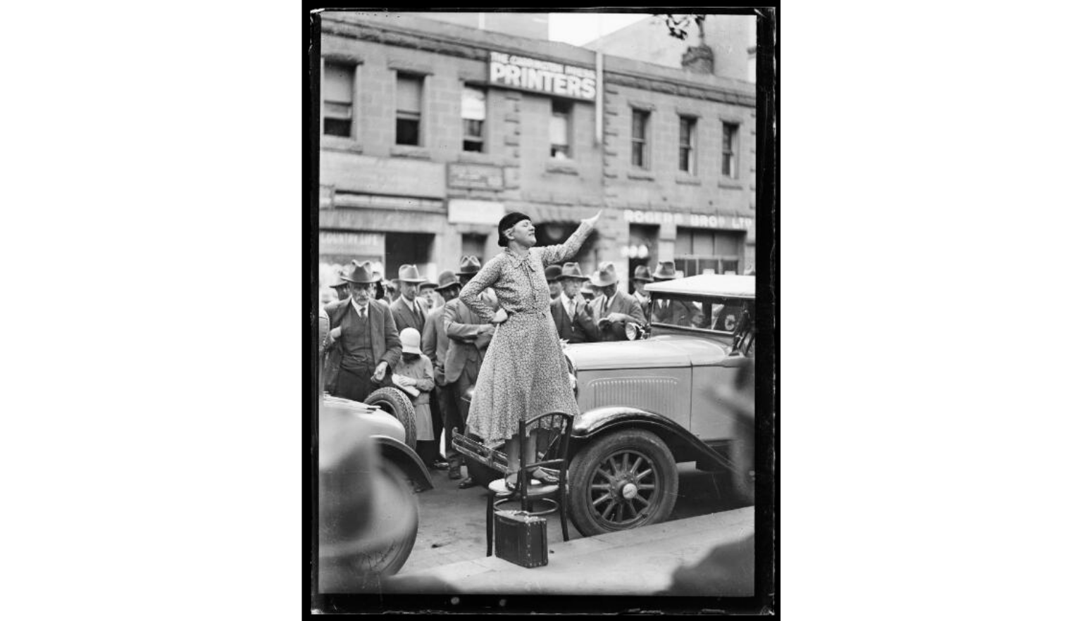 Black and white picture of Adela Pankhurst Walsh standing on a chair giving a speech outside The Carrington Press Printers, New South Wales