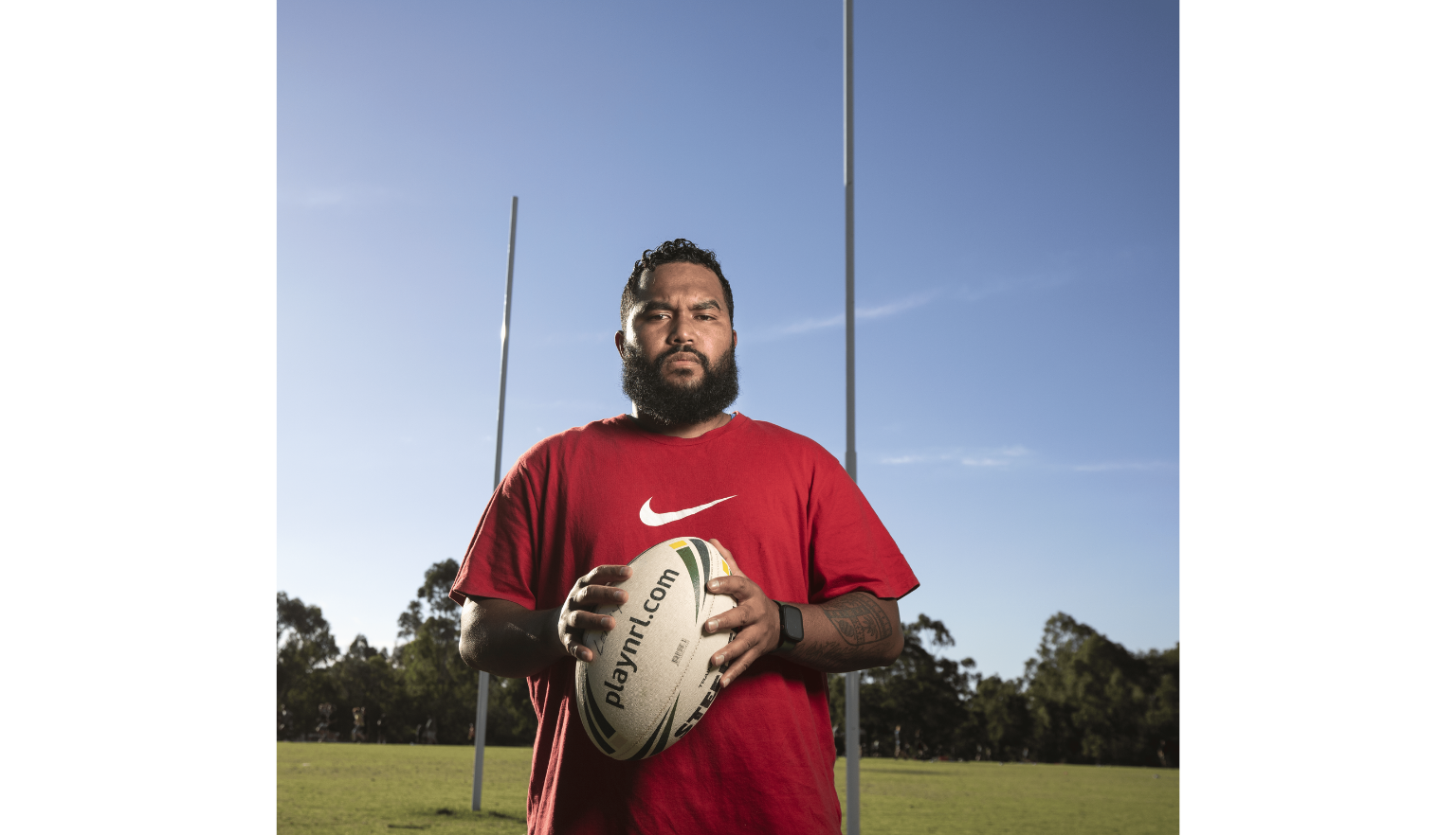Portrait of Dylan Wolfgramm, who is wearing a white shirt with the Nike logo holding a football on a NRL field