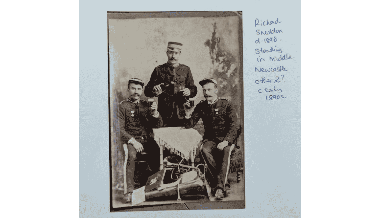 A sepia photograph featuring three men in formal attire, posing together.