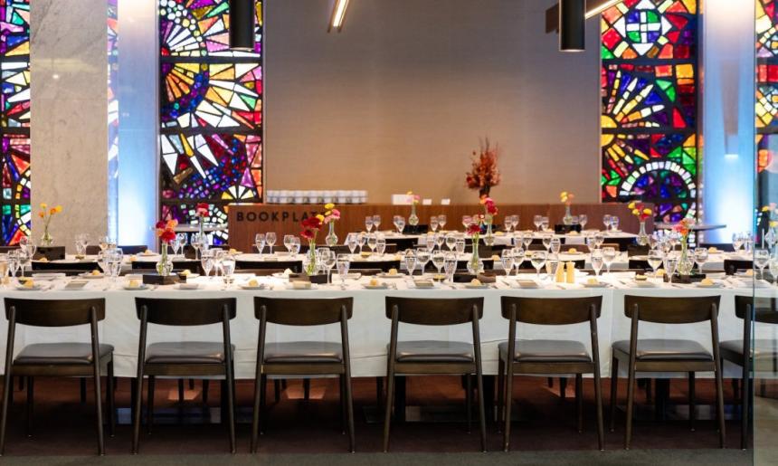 Bookplate cafe at the Library set up with long tables set with white table cloths, wine glasses and flowers