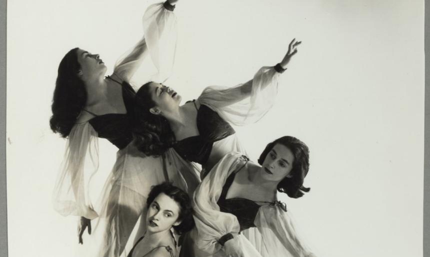 Four ballet dancers posing with their arms out and leaning in various directions