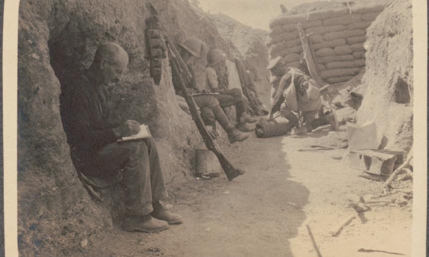 Sepia toned photo of soldiers sitting in a trench writing letters