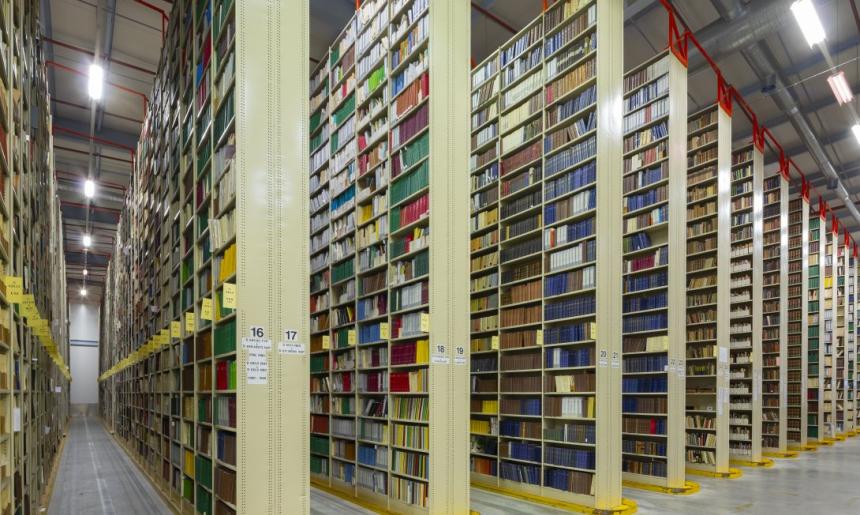 Rows of very tall, large bookshelves (stacks) in a warehouse