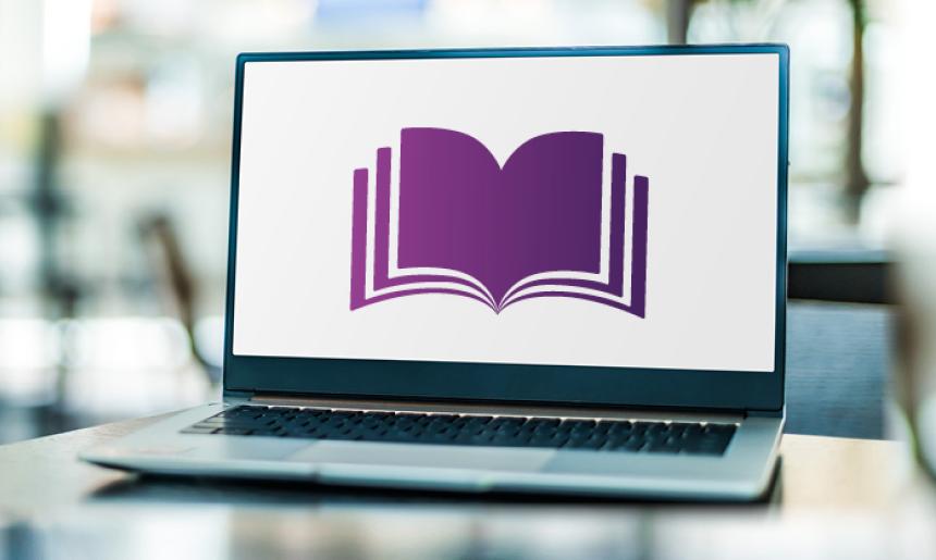 A laptop sitting on a desk with a stylised purple book on the screen.