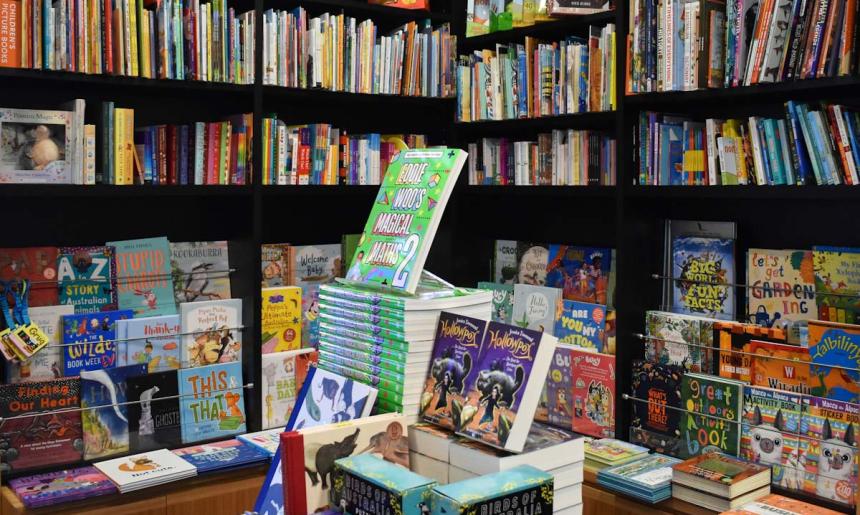 Lots of children's books on bookshelves and displayed on a table.