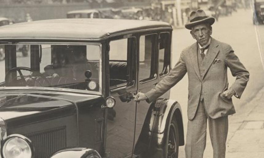 Billy Hughes standing next to a car
