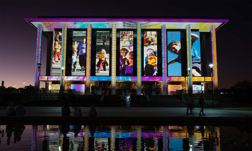 The National Library of Australia building at dusk, lit up with colourful projections.