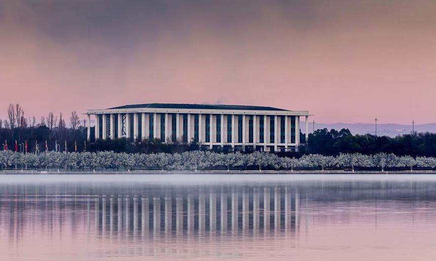 View of the National Library of Australia with a reflection of the building appearing in the water.