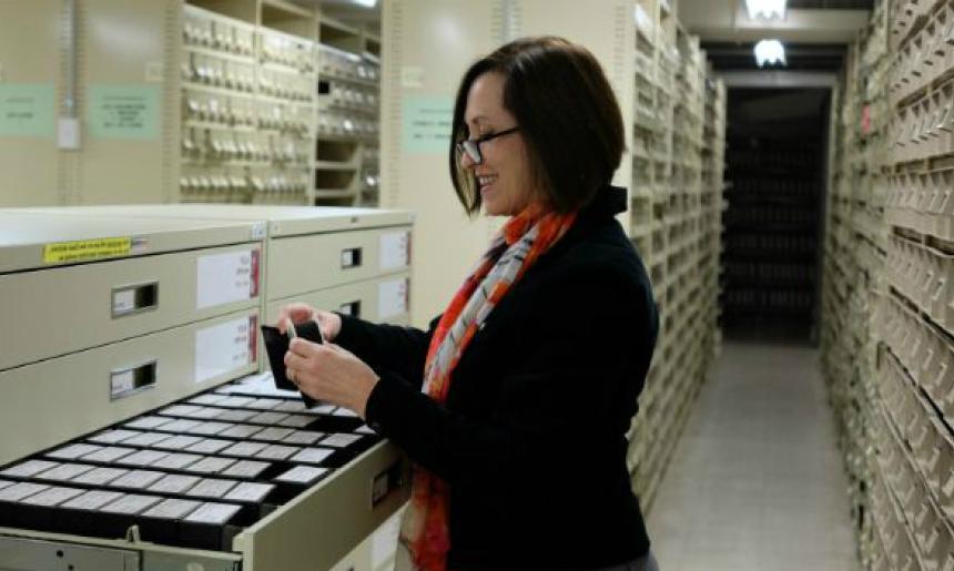 Woman looking at items in a filing cabinet in library stacks