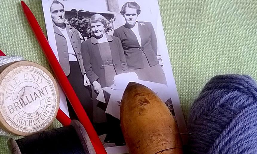 An image of a black and white photo, some yarn and sewing cotton and knitting needles on a green background. 