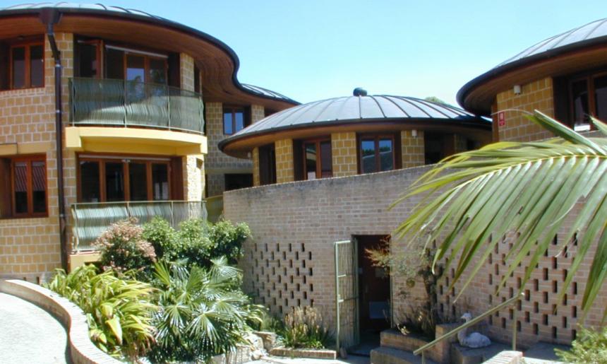 Brick building with curved walls and roofs, plants outside and a blue sky in the background