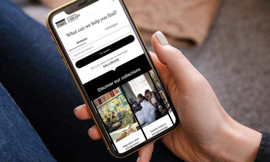 Hand holding a mobile phone open to the Library website homepage