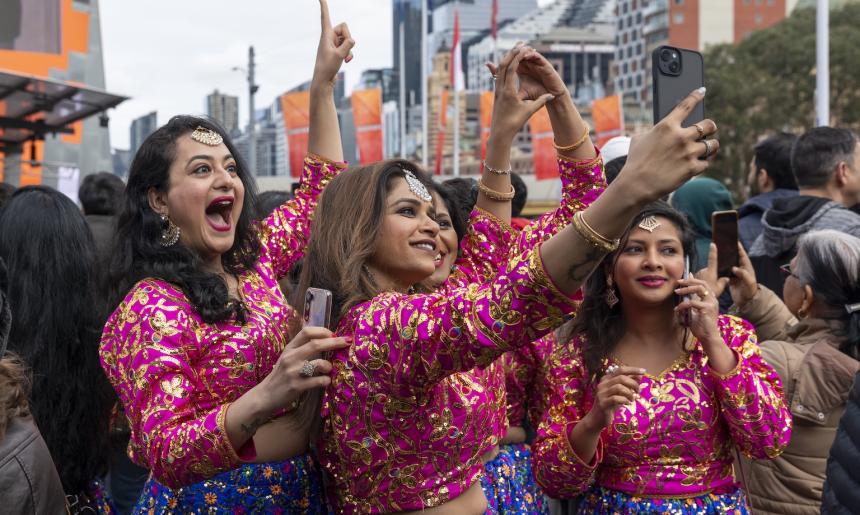 Photo of women from the dance group Bollydance Dipti in pink costumes taking a selfie in a crowd