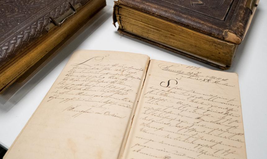 Three leatherbound diaries from the nineteenth century, one open showing neat handwriting