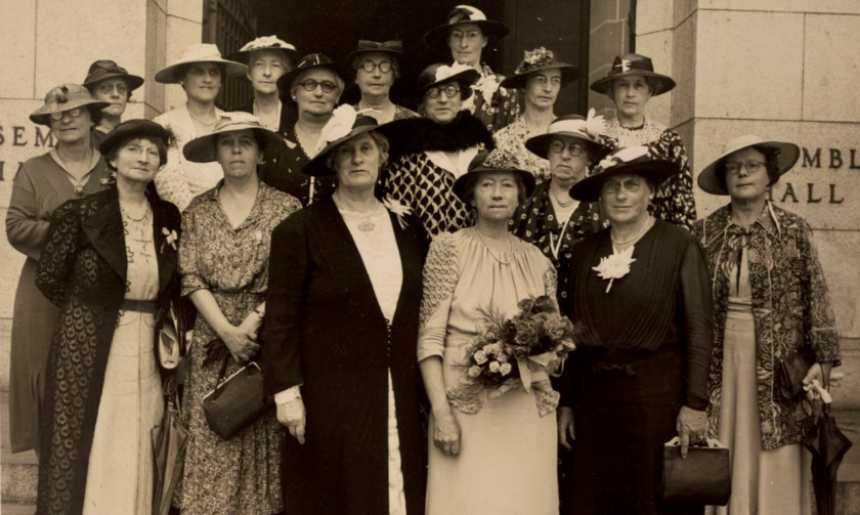 Sepia-toned photo of 16 members of the Australian National Council of Women standing with Dame Maria Ogilvie Gordon on the steps in front of a building