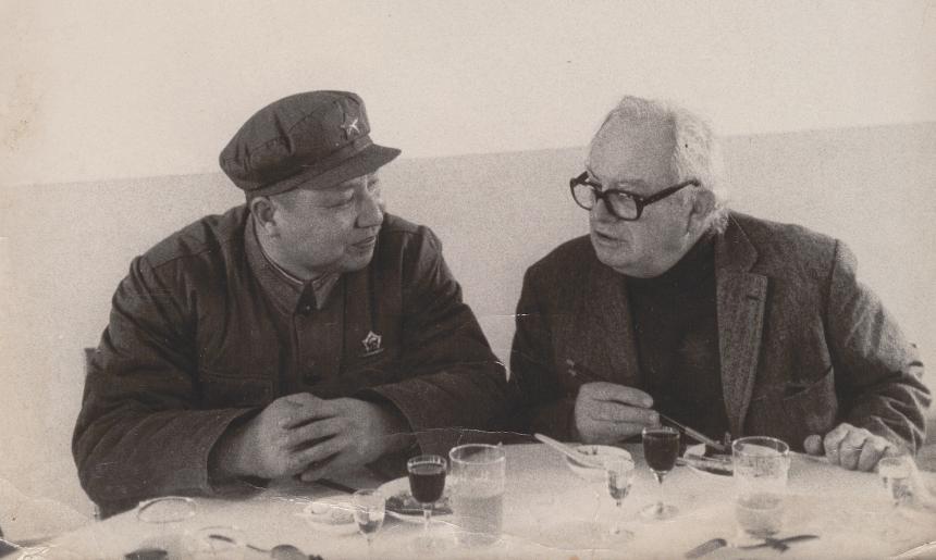 Two men, Wilfred Burchett and Mao Zedong sitting at a small table and talking over a meal