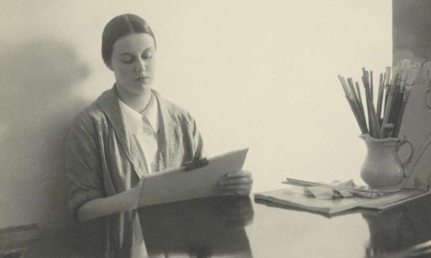Portrait of Nora Heysen sitting at a desk and painting
