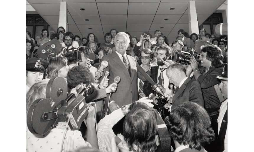 Black and white photo of Gough Whitlam speaking at Parliament House surrounded by reporters