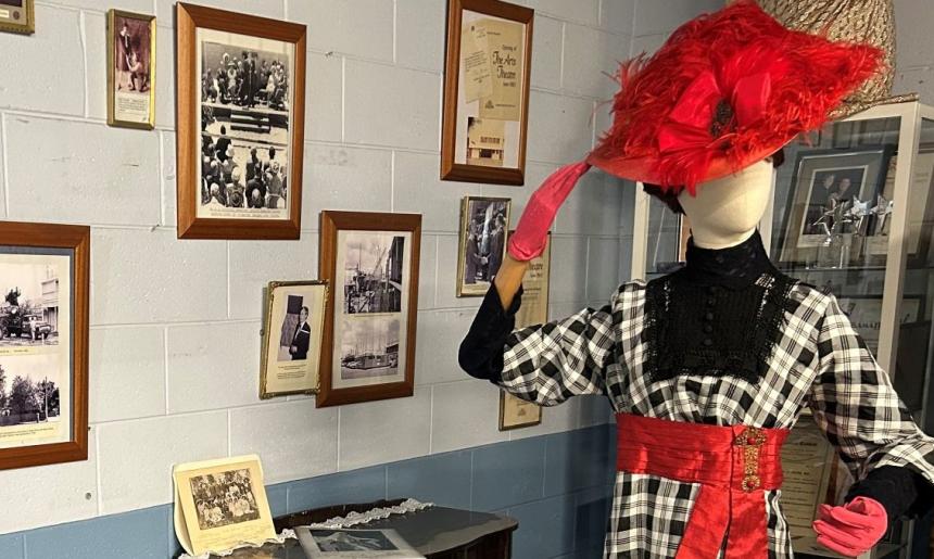 A display of items from the Adelaide Repertory Theatre collection including a mannequin wearing a costume and framed photographs hanging on a wall.