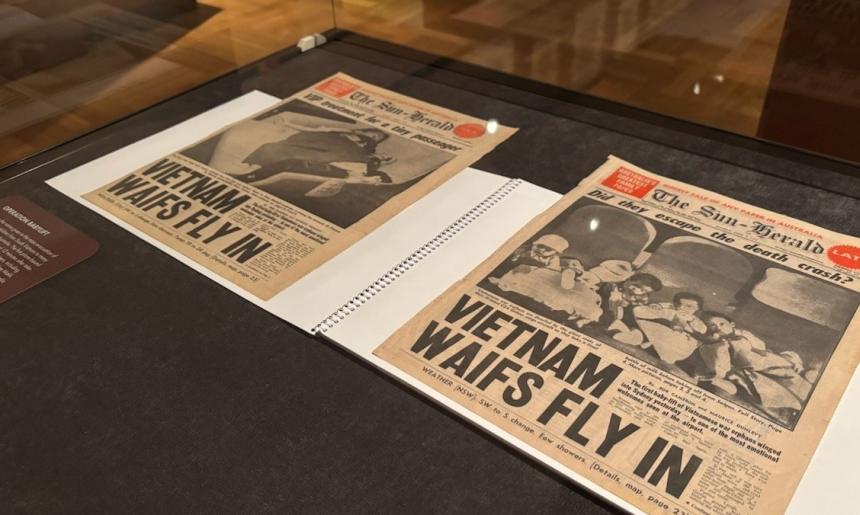Two newspaper front covers in a display case. The headline on both reads, 'Vietnam waifs fly in'.