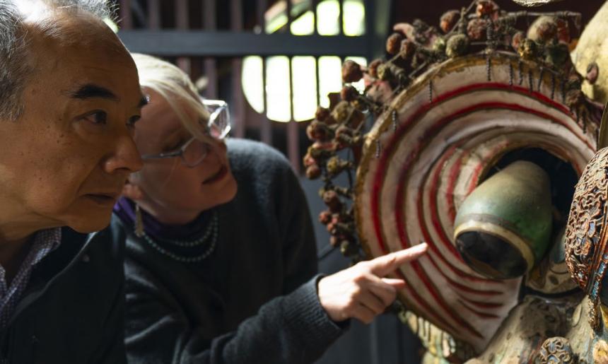 Two people leaning over and looking at a dragon head.