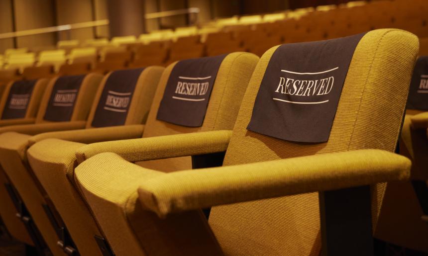 A row of empty theatre seats with 'reserved' signs