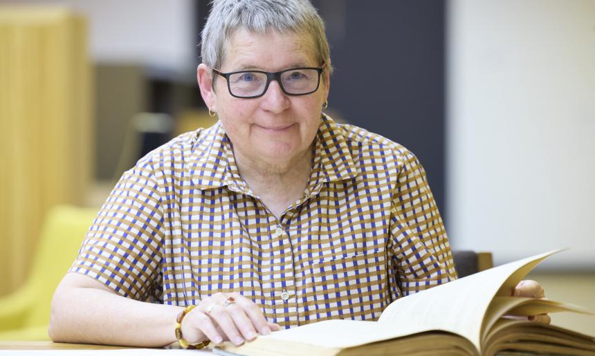 A woman smiling with collection material in the National Library's Special Collections Reading Room