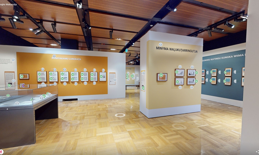 A wide-angle view inside an exhibition gallery. The walls feature illustrations and photographs with descriptive text.