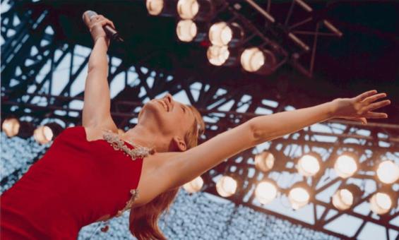 Kylie Minogue wearing a red dress and with her arms in the air