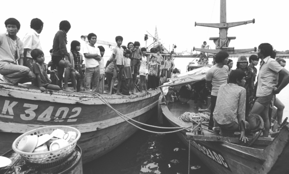 Two boats with rope hanging between them filled with men, women and children coming from Vietnam