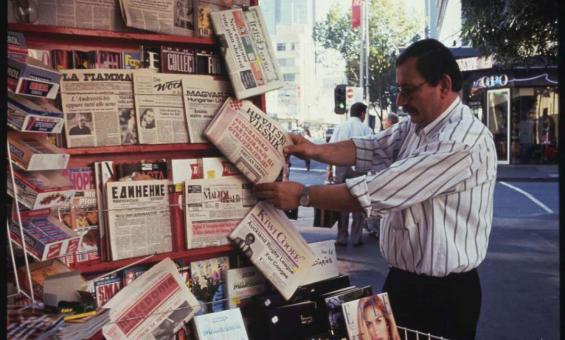 A man looking at newspapers in multiple languages at a newspaper kiosk on Elizabeth Street, Melbourne.