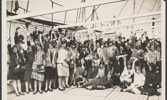 Black and white photo of British migrant women waving on the deck of a ship