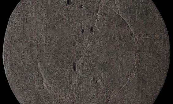 Image of a pock marked copper plate with writing inscribed across it from top to bottom.