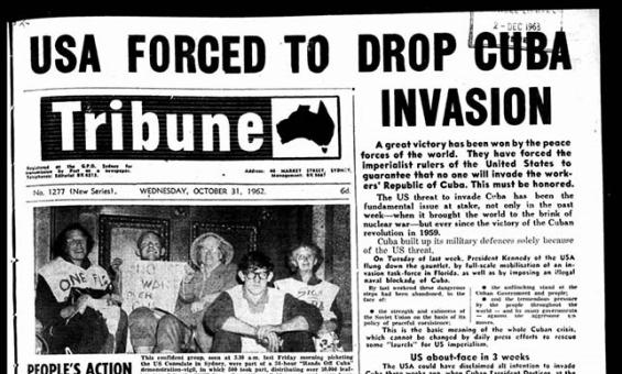 The front page of the Tribune newspaper. The headline reads 'USA FORCED TO DROP CUBA INVASION'. There is a black and white photograph of 5 people holding protest signs.