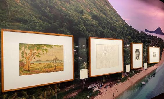 Four framed pictures hanging on a wall that has an image of an island on it.