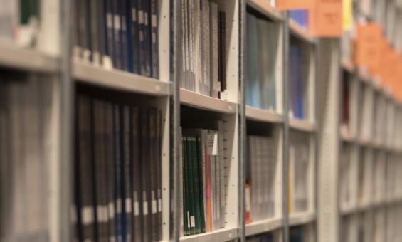 Long shelves of books and other print material with regular orange signs