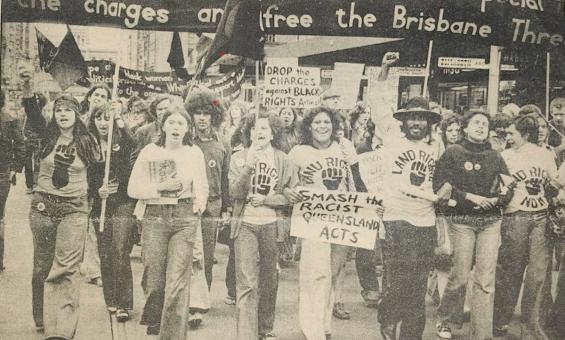 A sepia image of a group of people marching in a protest for Australian First Nations land rights