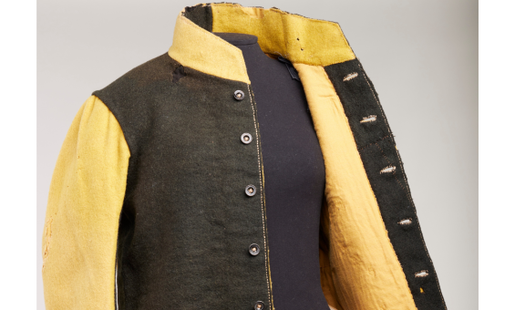 Black and yellow uniform made up of a long-sleeve button up jacket on a mannequin