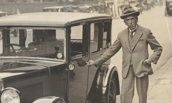 Billy Hughes standing next to a car