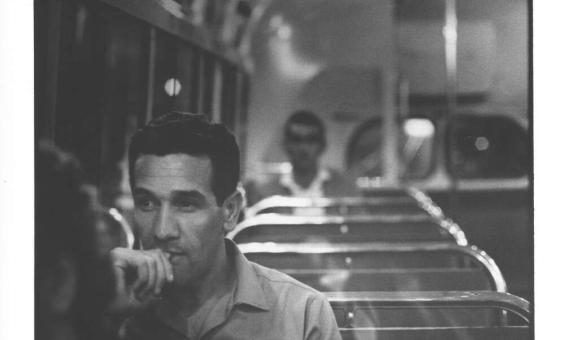 A black and white photo of a man sitting on a train