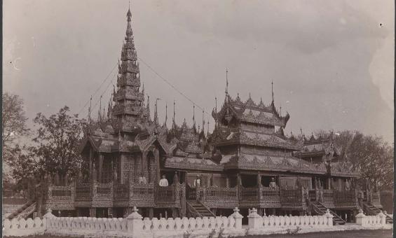 Sepia photograph of a monastery with people stanidng on the balconies
