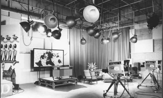 Black and white photo of a television studio from the 1960s, with large cameras, screens and spotlights